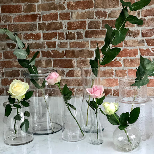 collection of vases on worktop with one stem of rose in each